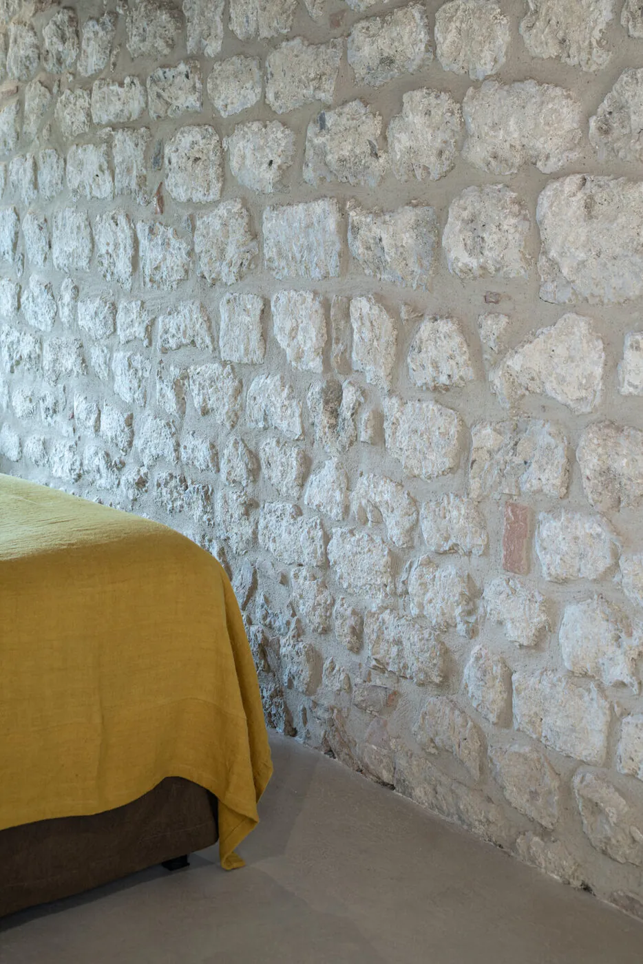 Copriletto in lino antico ritinto, su muro in pietra